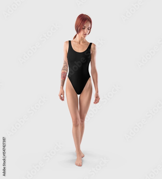 Fototapeta Mockup of a black sports swimsuit on a slender redheaded girl with a tattoo, front view, for design, branding.