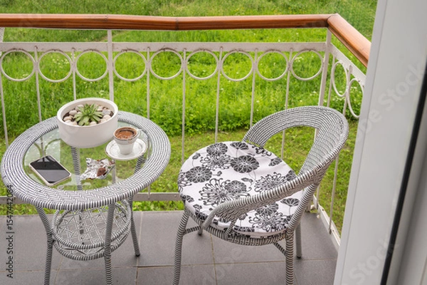 Fototapeta A cup of coffee, a smartphone on a glass table on a balcony.	