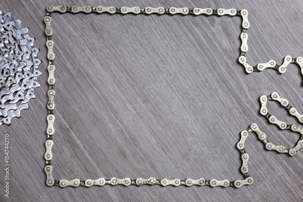 Fototapeta White metal rusty and oily assorted items, bicycle parts like chain and cassette related with bicycle repair on a wooden background with copyspace