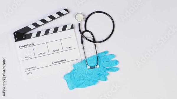 Fototapeta Clapperboard with stethoscope and latex glove on white background.