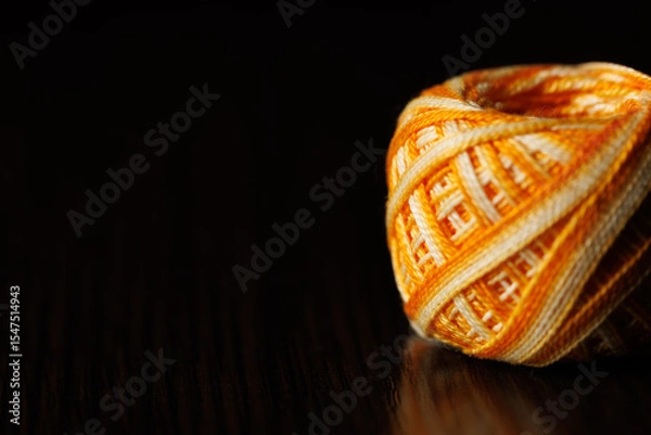 Fototapeta A skein of colored melange threads lies on a dark wooden table. Selective focus. Place for text. Copyspace.