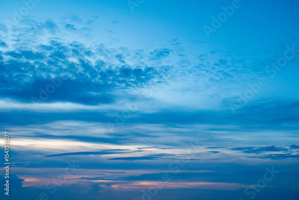 Fototapeta Blue sky with a pink stripe at the horizon. Calm background with evening clouds.