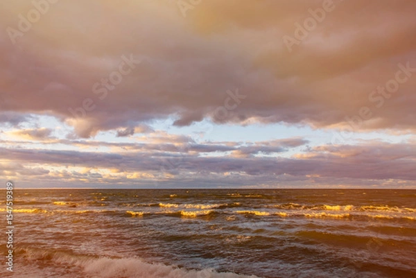 Fototapeta Dark sky over the sea. Low clouds over the water in the bay. Background with a tense panorama of the coast before a storm at sunset.