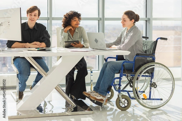 Fototapeta Teamwork brainstorm. Diverse multiracial colleagues woman in chair for people with disability working together. Group of people sitting in creative office discussing business. Young professional team