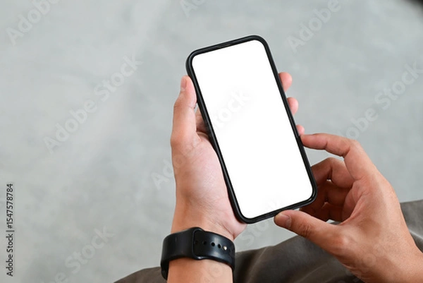 Obraz A person is holding a cell phone with a black band on their wrist. The phone is turned off and the screen is blank