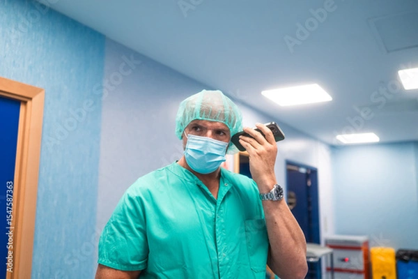Fototapeta Surgeon using smartphone in hospital corridor
