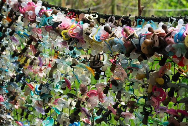 Obraz Colorful baby pacifiers on the fence. The place where babies refuse to use pacifiers anymore