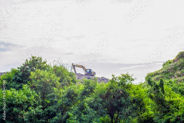 Obraz View of an excavator on a pile of rubbish from a distance, an overloaded landfill in Slamaran Pekalongan, Central Java