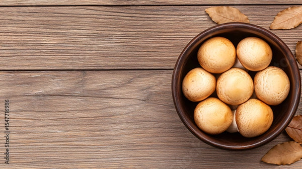 Fototapeta Fresh brown mushrooms are piled high inside a rustic bowl placed on a weathered wood surface.