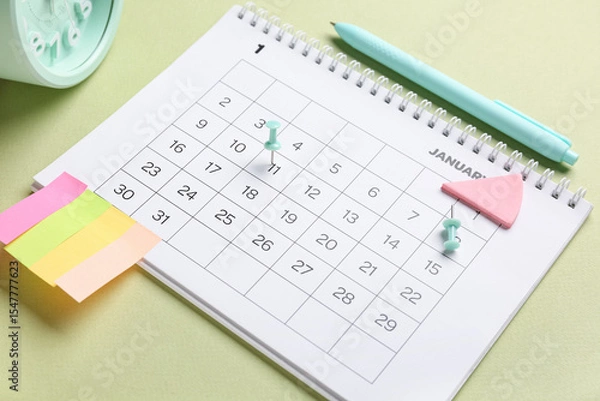Obraz Calendar with alarm clock, stationery and sticky notes on green background. Planning concept