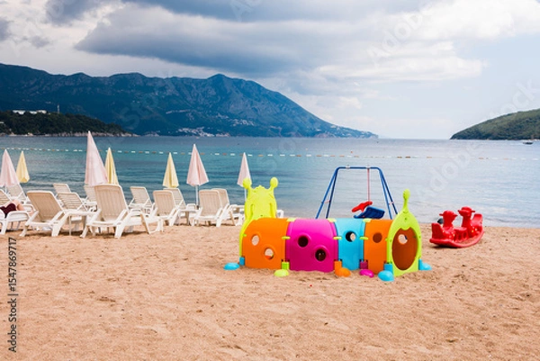 Fototapeta Colorful children's playground on a sandy beach. Seaside recreation, summer vacation, and family-friendly tourism by the coast.