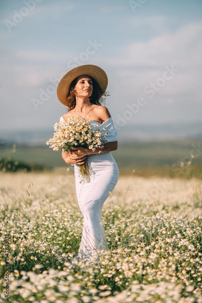 Obraz Woman Daisies Field: Summer day, lady with bouquet stands in blooming daisies field, looks into distance.