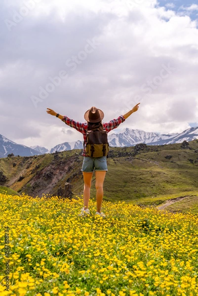 Obraz Backpack Flowers Mountain: Hiker with open arms in a meadow enjoys the view during mountain trip.