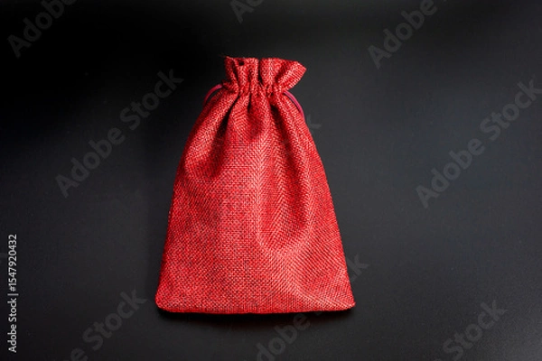 Fototapeta Elegant red fabric gift bag on black background with drawstring closure