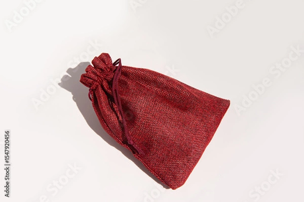 Fototapeta Elegant red burlap drawstring gift bag against a plain background