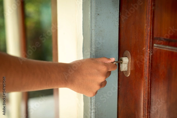 Fototapeta A woman's hand is using a key to open the door of the house