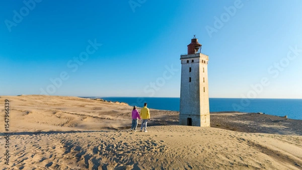 Fototapeta Explore the iconic lighthouse of Rubjerg Knude on the sandy coastline in Denmark during sunset