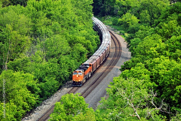 Obraz Diesel locomotive coming around a curve pulling a freight train comprised of grain cars