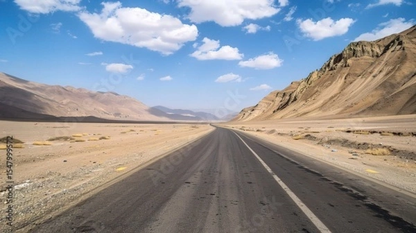 Fototapeta  A highway in the desert of Tibet, with a blue sky and white clouds, mountains on both sides, captured in high-definition photography. 