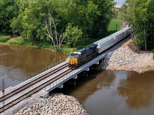 Obraz Aerial view of a diesel locomotive crossing a bridge over a small waterway
