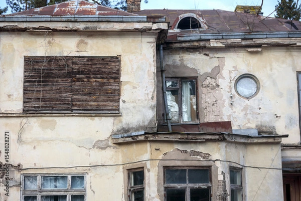 Fototapeta 
an old, worn-out building facade with several windows and doors, indicating its abandonment or poor condition.