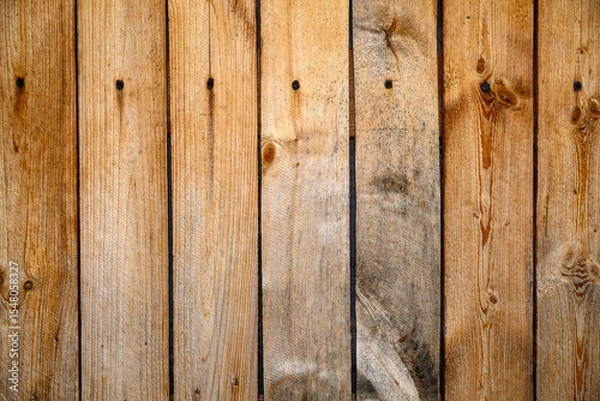 Fototapeta The vertical wooden planks are placed closely together, highlighting their natural grain and warm tones. The wood has a rustic look, with various knots and imperfections for copy space.