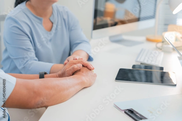Fototapeta Asian doctor in uniform attentively assists a senior couple with medical paperwork in a hospital area, explaining health records and test results with care and professionalis senior health