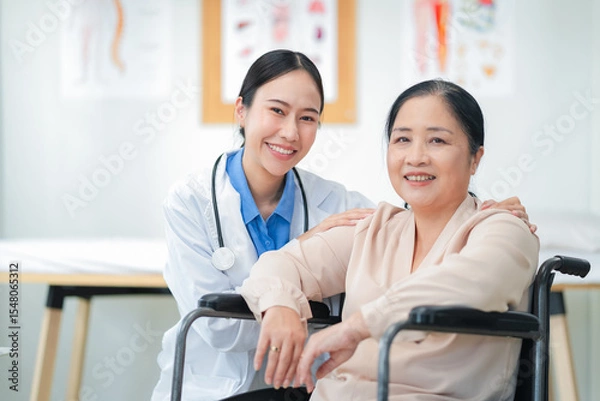 Fototapeta Asian female doctor giving a cheerful high five to an elderly woman patient, both smiling warmly in a medical clinic setting. A joyful moment of healthcare connection, trust, and support between careg