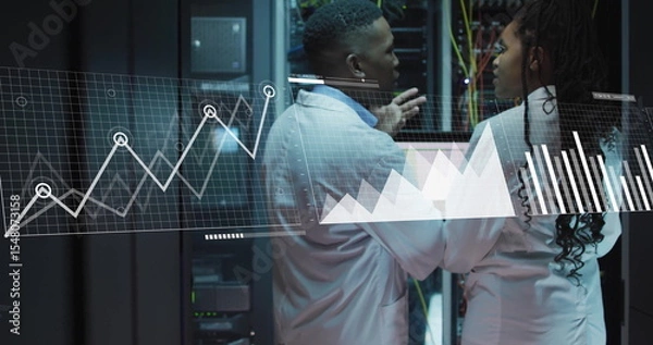 Obraz Gesturing engineers in lab coats reviewing metrics on laptop in data center, with racks and cables