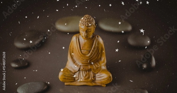 Fototapeta Displaying wooden meditating statue sitting on tabletop with river stones and white star overlays