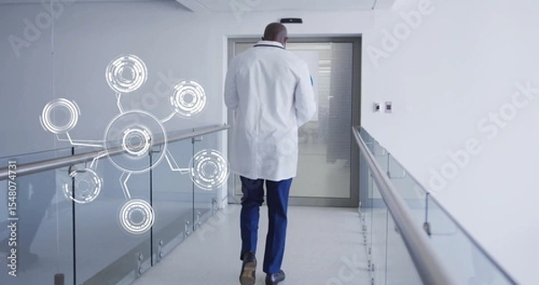 Obraz Walking doctor wearing lab coat down hospital hallway, with glass railing, digital network overlay