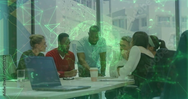 Fototapeta Team members leaning over laptop, documents, coffee cups around office table, with hologram globe