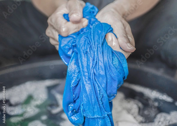 Fototapeta Washing clothes by hand in the traditional way without using a machine.