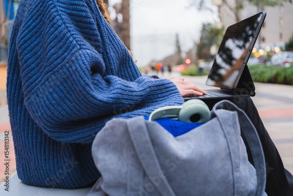 Fototapeta College student working on tablet in urban park, enjoying fresh air and technology