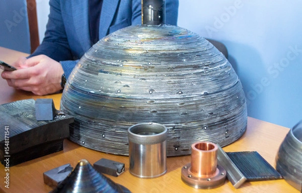 Fototapeta Objects printed on 3D printer from filament of molten metal on table. Object printed by 3D printer from metal. Additive manufacturing solution. Object created on 3D printer from melting metal thread
