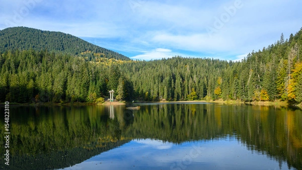 Fototapeta Mountain lake Synevir, Ukraine. View of Synevir high-altitude lake by autumn day. The leaf fall forest, lake and mountains.
