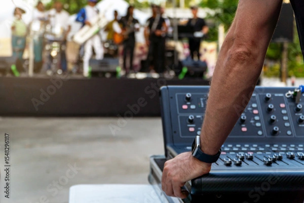 Fototapeta Sound technician controlling soundboard while music band plays on the stage on a music festival