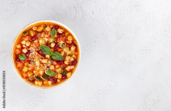 Fototapeta Italian vegetarian soup with vegetables, pasta on white background. Minestrone soup. Italian food. Top view. Copy space.