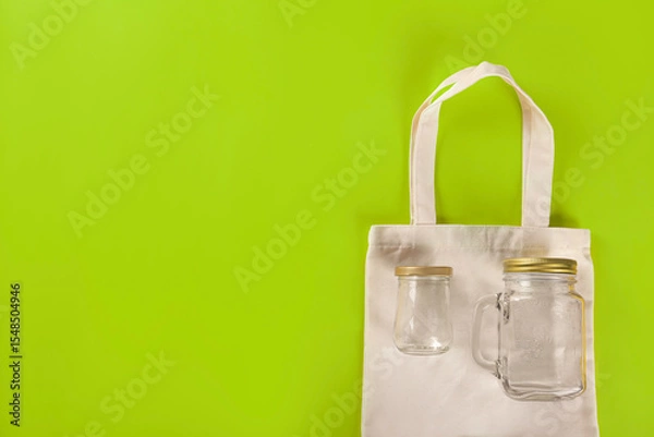 Obraz Eco bag with empty reusable empty bottles on light green background. top view