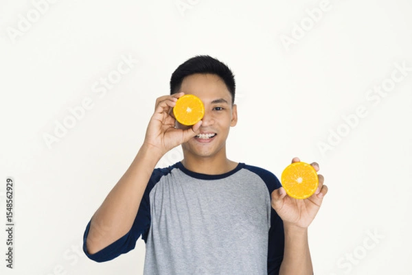 Fototapeta Smiling Man Holding Orange Halves with Joyful Expression on His Face