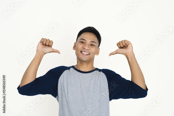 Fototapeta Young man in a gray shirt enthusiastically gesturing, showing excitement and joy on a white background.