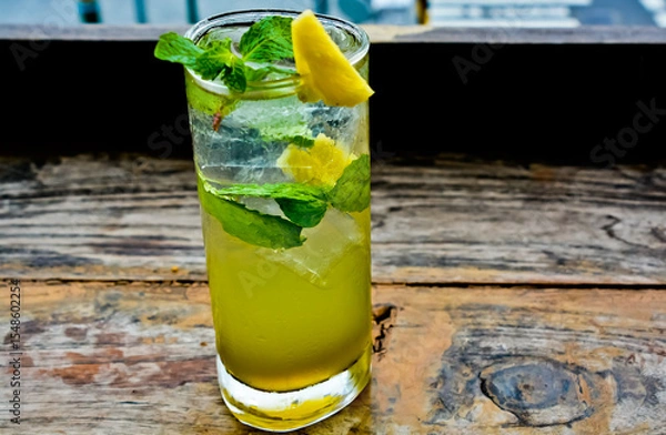 Fototapeta view of a glass of lime ice with mint leaves and lemon topping