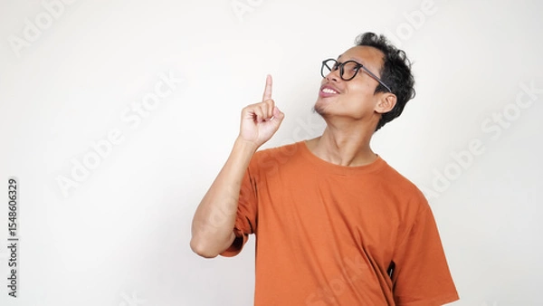 Obraz A man in an orange shirt is smiling and pointing to the camera