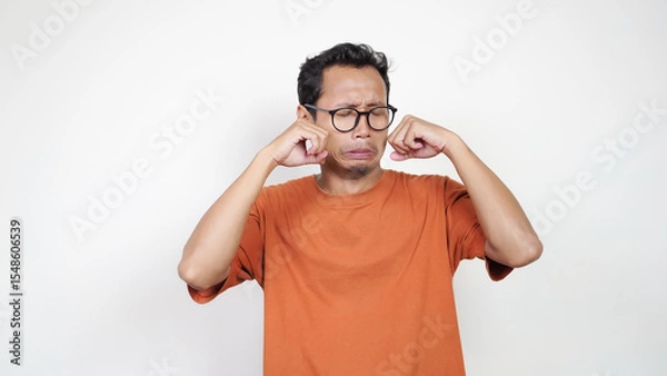 Obraz A man in an orange shirt is wearing glasses and is making a face