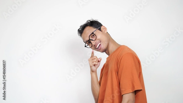 Obraz A man in an orange shirt is smiling and pointing to the camera