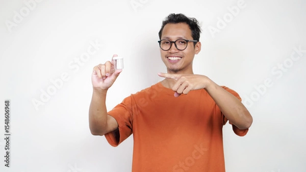 Obraz A man in an orange shirt is holding a clear container