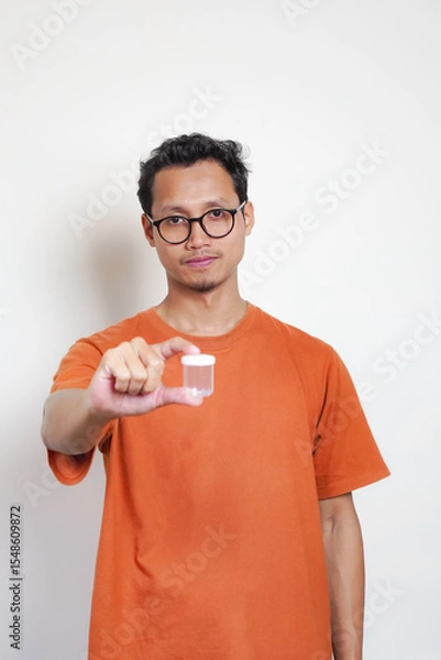 Obraz A man in an orange shirt is holding a clear container