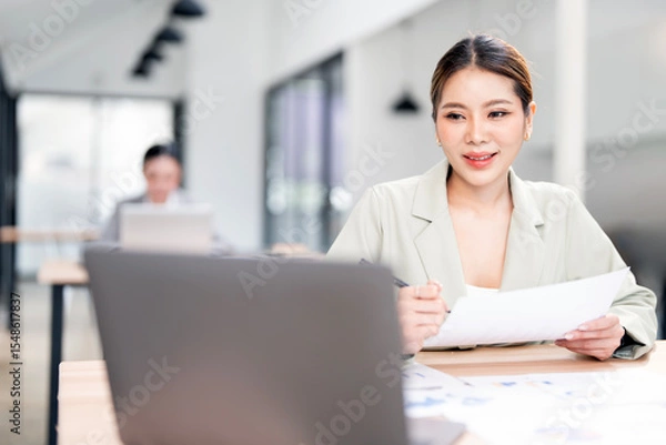 Obraz portrait of an attractive young businesswoman working on her laptop while sitting in the office.