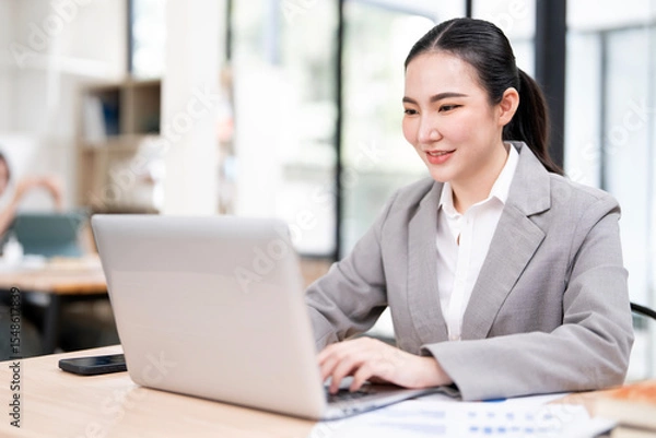 Obraz portrait of an attractive young businesswoman working on her laptop while sitting in the office.