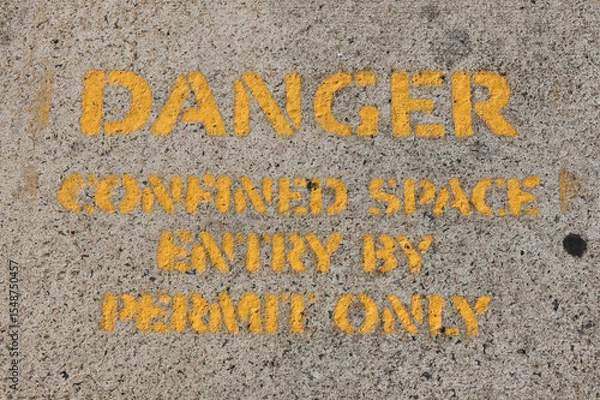 Fototapeta Danger - Confined Space - Entry By Permit Only sign painted in yellow on a concrete surface